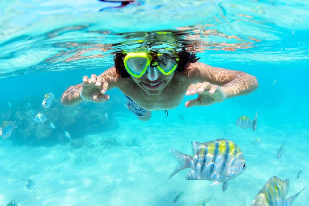 Criança fazendo mergulho em piscinas naturais e nadando com peixinhos no Alagoas.