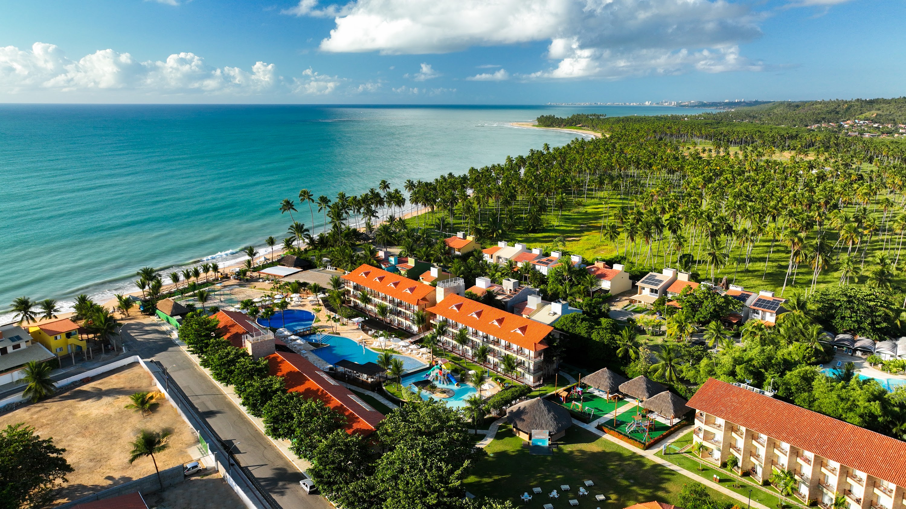 Vista aérea do Salinas Maceió Resort, com piscinas, área verde e a praia ao fundo, destacando a natureza exuberante e a costa alagoana.