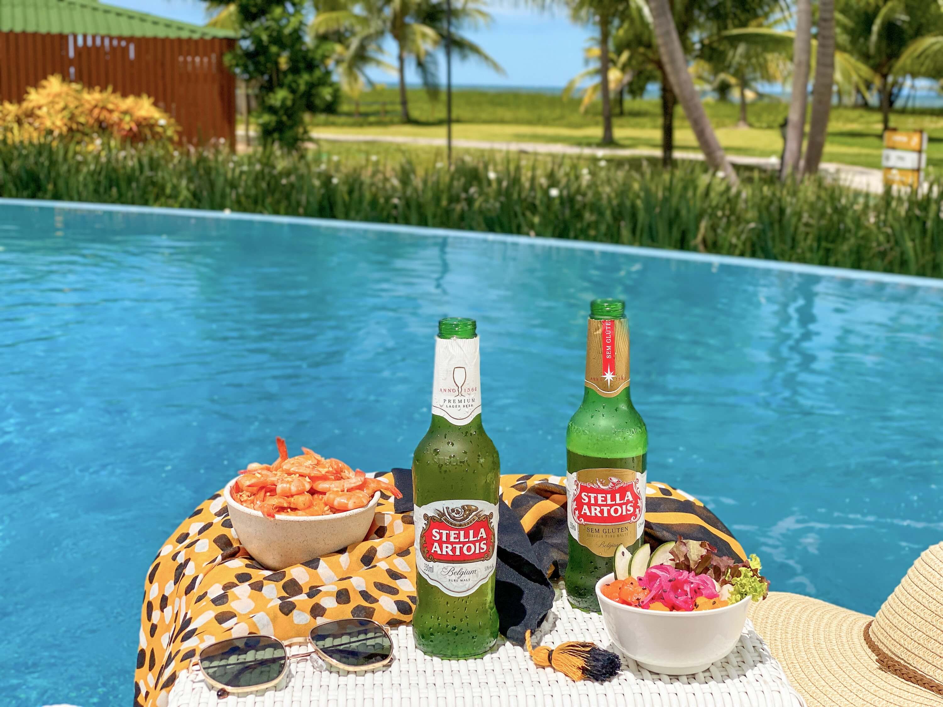 Cerveja e petiscos em cima da mesa à beira da piscina do Slinas Maragogi All Inclusive Resort.