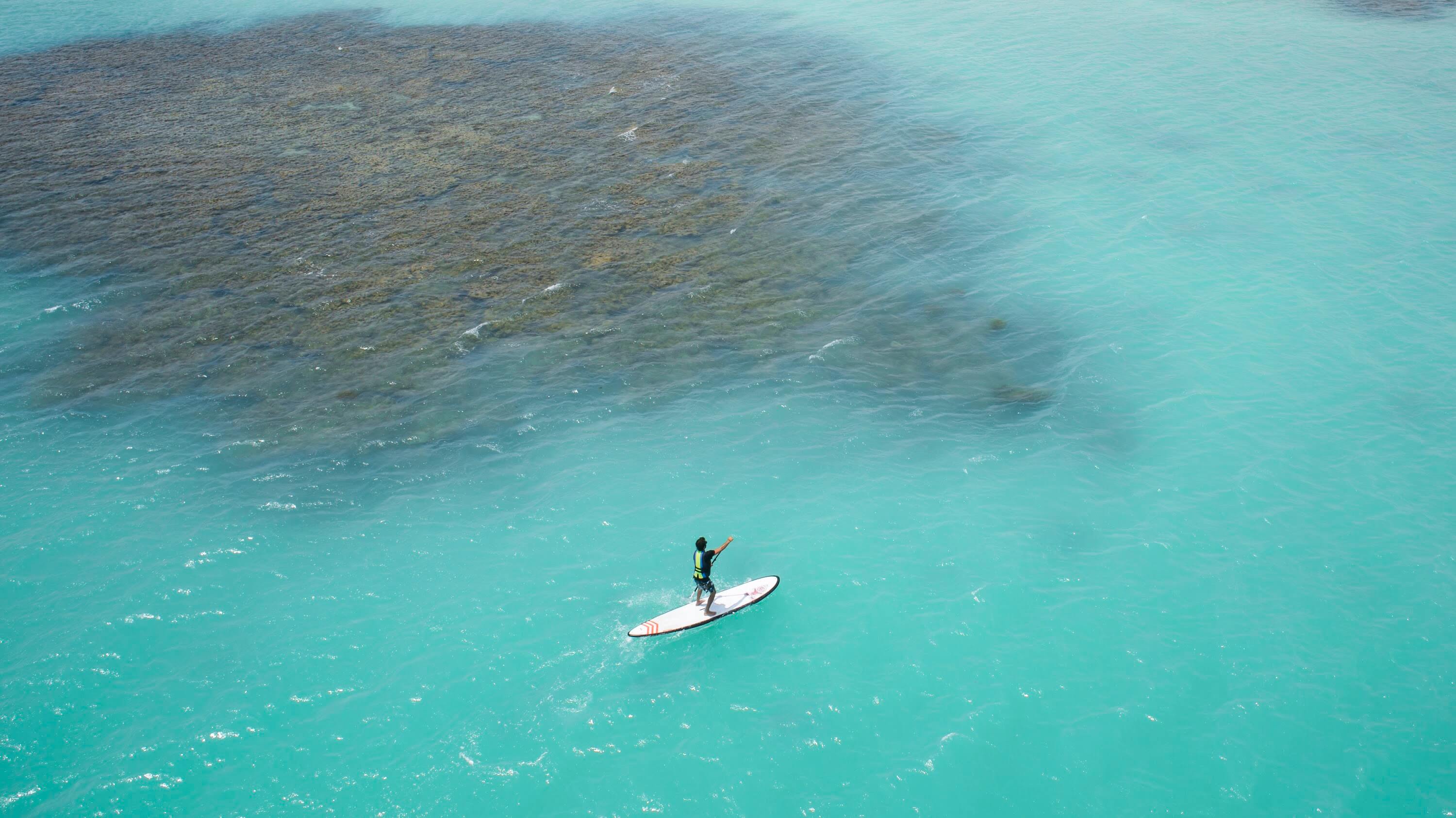 Homem sobre stand up paddle nas piscinas naturais de Japaratinga.