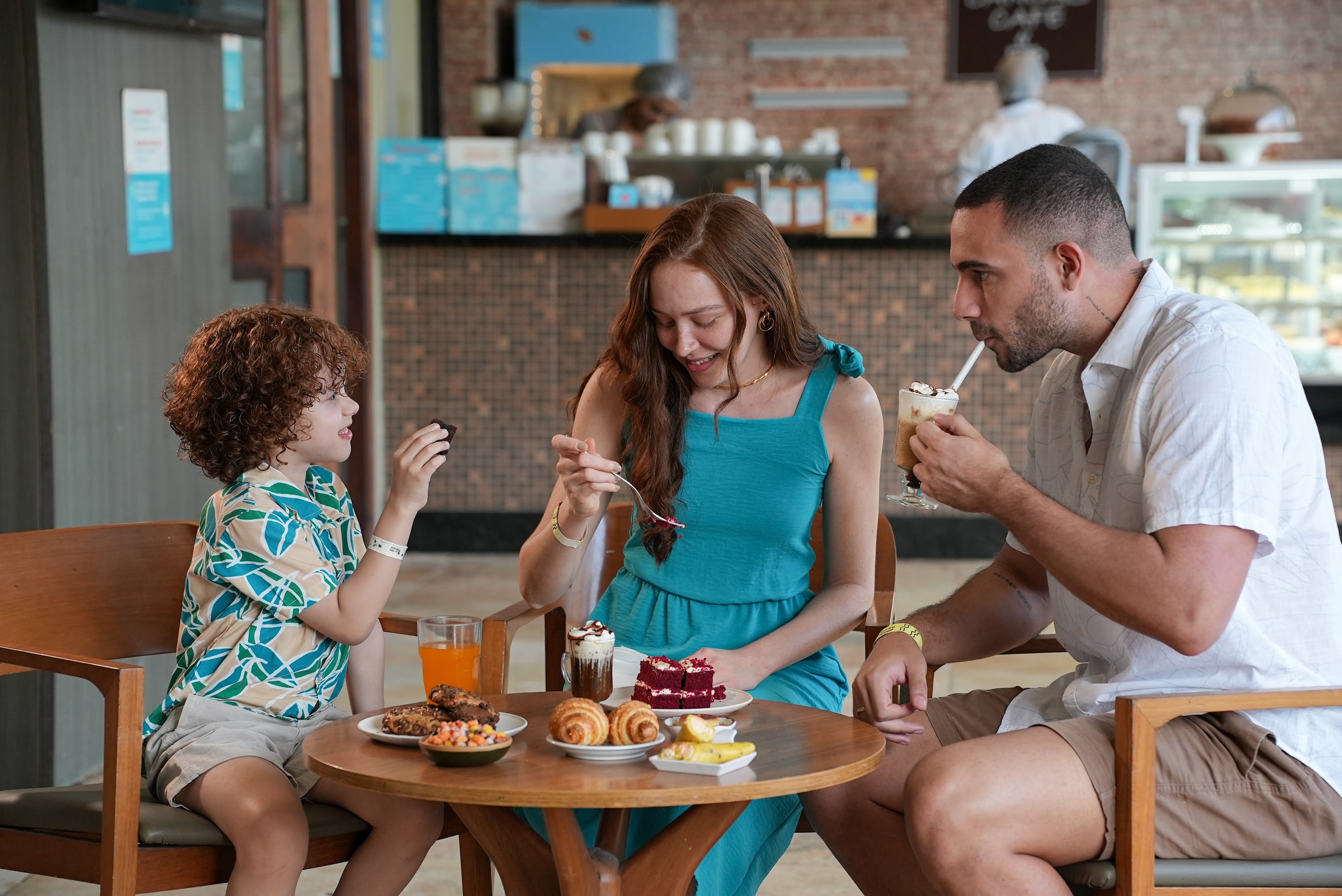 Família feliz desfrutando lanches e petiscos no Espaço Canoas, ponto de consumo do resort All Inclusive Salinas Maceió.