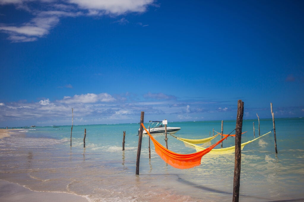 praia com redes representando os lugares para conhecer no Brasil