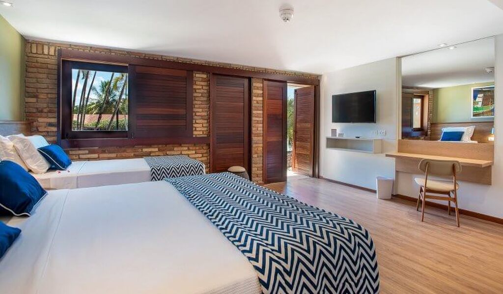 Imagem de uma suíte de hotel moderna com duas camas, decoração aconchegante, TV de tela plana e vista para o jardim.